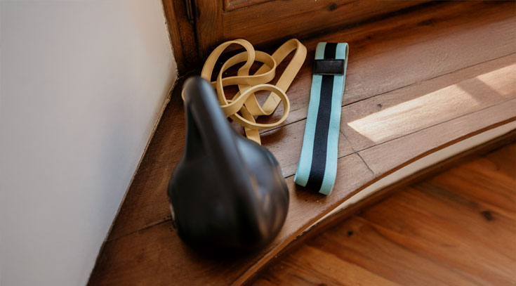 Equipamiento básico como kettlebell y bandas elásticas para trabajar la movilidad y acelerar la recuperación muscular sin salir de casa.