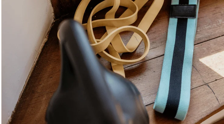 Mujer entrenando con banda elástica y kettlebell en casa como ejercicio para la sarcopenia.
