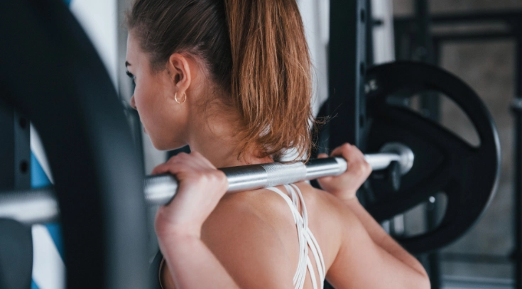 Mujer levantando pesas en el gimnasio, un ejercicio fundamental para estimular el aumento de testosterona.